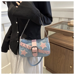 Detail of blue denim and pink leather bag with star patches and metal chain strap