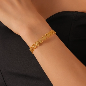 Close-up of intricate hollow flower link bracelet in gold finish worn on wrist