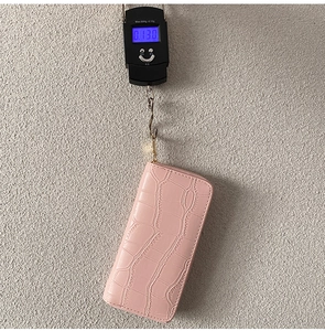 Detailed view of pink PU leather wallet with crocodile pattern weighing 0.130kg on a scale