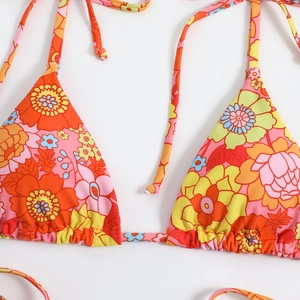 Detail of vibrant retro floral print and ruched texture on bikini top with drawstrings