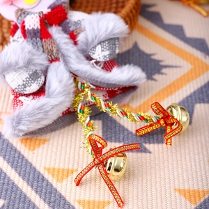 Close-up of plush snowman Christmas ornament with red knit scarf and golden bells