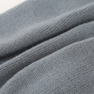 Detaillierte Makroansicht der weichen grauen Strickstruktur einer Kinderwintermütze