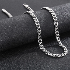 Detailed macro view of high-gloss silver Cuban chain necklace on a premium black stand