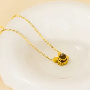 Golden 12 zodiac rabbit projection necklace with dark gemstone inlay in elegant white bowl