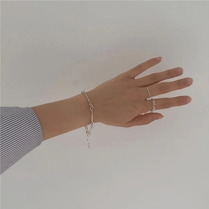 Detail shot of a minimalist 925 silver twist bracelet and matching rings worn by a model
