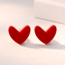 Vista macro di orecchini a lobo minimalisti a forma di cuore rosso con finitura lucida