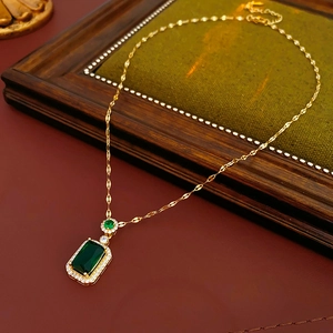 Detailed view of emerald green rectangular necklace with diamond accents on wood background