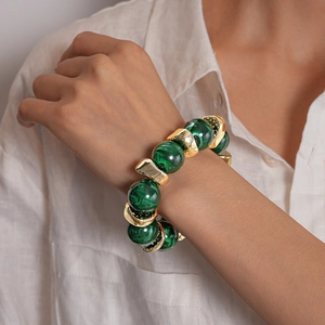 Primo piano di un bracciale con grosse perle di marmo verde e maglie in metallo dorato