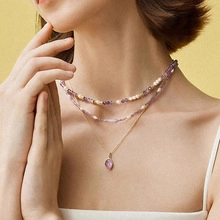 Close-up of layered necklace with freshwater pearls, purple stones and gold pendant