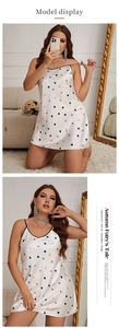 Detail view of white silk pajamas featuring colorful heart prints and black lace trim