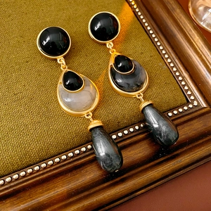 Detailed view of vintage gold flower earrings with black and grey drop stones on fabric