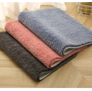 Detailed plush texture of bathroom mats in blue, pink, and grey with non-slip backing