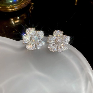 Macro detail of silver floral stud earrings with sparkling zircon stones and petals