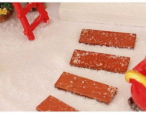 Close-up of miniature red wood stairs with artificial snow for Christmas dollhouse decor