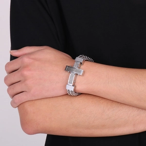Macro detail of men's stainless steel cross bracelet with rugged curb chain links