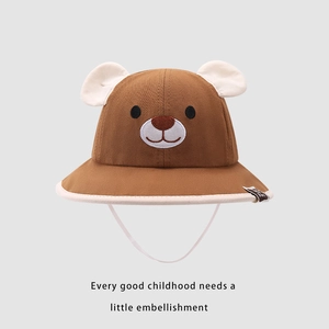 Detail of dark brown baby sun hat featuring 3D bear ears and a white chin strap
