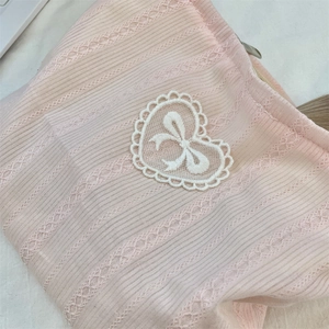 Detail of pink ribbed fabric cosmetic bag with heart lace embroidery and bow motif