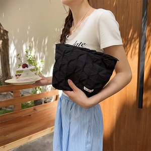 Detailed texture of black pleated quilted pouch with colorful woven label tag
