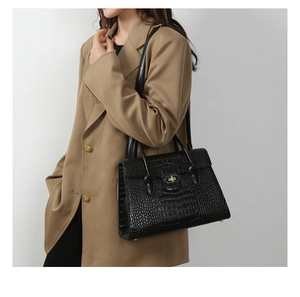 Model wearing a black crocodile embossed handbag with premium gold hardware lock detail