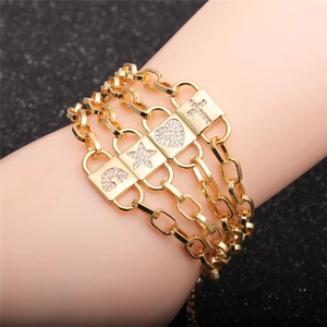 Detail of a gold multilayer bracelet featuring zircon cross, heart, star and rainbow charms