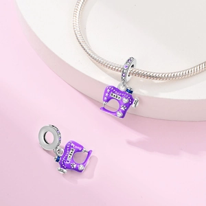 Detailed view of silver sewing machine charm with purple enamel and zircon accents