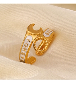 Close-up of golden wrench ring with white enamel detail and engraved lettering