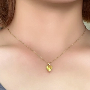 Close-up of heart-shaped yellow zircon pendant on a gold necklace worn by a model