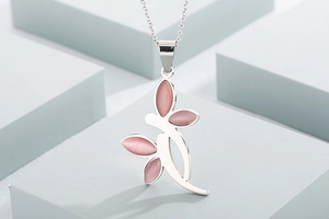 Detail view of flower pendant necklace with pink cat eye stones on geometric blocks