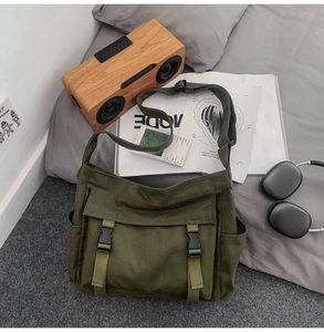 Détail du sac messager en toile vert armée avec boucles sur une décoration de lit décontractée