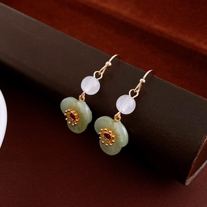 Detail of elegant resin jade flower earrings with gold petals and white bead accent