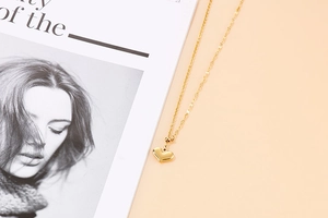 Detail shot of heart pendant necklace with gold finish on a fine cross chain