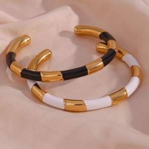 Detail of 18K gold-plated bracelets with black and white enamel segments on satin fabric