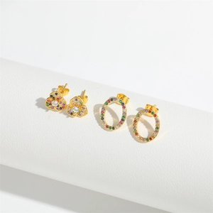 Golden clover and oval stud earrings with colorful cubic zirconia on white pedestals