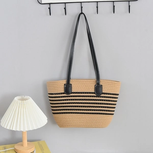 Detail of a large khaki woven tote bag with black stripes hanging on a wall hook