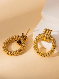 Detailed macro view of large gold titanium hoop earrings with bead texture and triple band accent