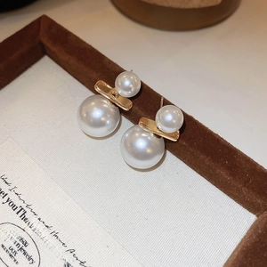 Minimalist double white pearl stud earrings with gold geometric bar in a jewelry box