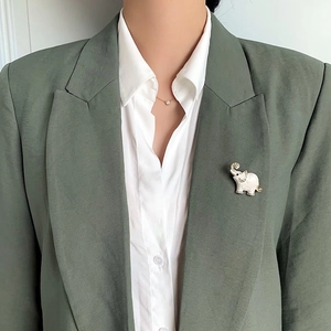 Elegant white elephant brooch with sparkling rhinestones on a green suit lapel