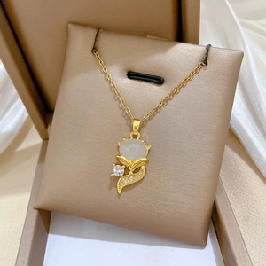 Macro detail of golden fox pendant necklace with opal stone in beige velvet gift box