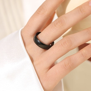 Detail of minimalist matte black stainless steel ring on model hand with elegant lighting