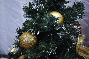Detail of mini Christmas tree featuring golden glitter balls and silk ribbon decor