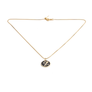 Close-up of golden necklace with a black round pendant featuring gold flower and star