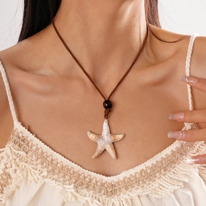Détail du collier pendentif étoile de mer avec cordon brun sur dentelle bohème