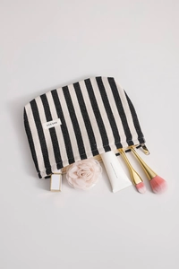 Flat lay of black and white striped canvas makeup bag with zipper and cosmetic accessories