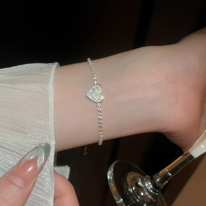 Close-up of gold heart pendant bracelet with shimmering zircon stones on dark background