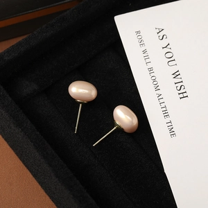 Macro detail of geometric square pearl earrings with gold S925 silver pins on black tray
