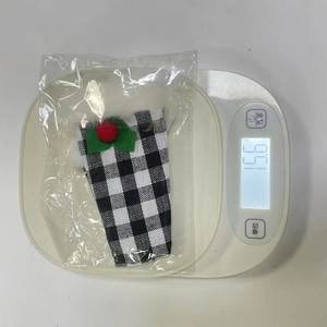 Detail showing product weight of 15.6g for a plaid Christmas wine bottle cover on a scale