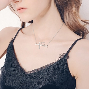 Detailed view of silver stainless steel heartbeat necklace with heart pendant on collarbone