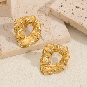 Irregular golden geometric hoop earrings with textured hammered finish on travertine stone