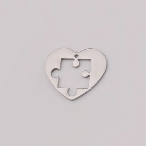 Polished silver stainless steel heart pendant with puzzle piece cutout on white background