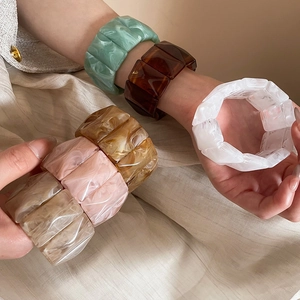 Close-up of faceted acrylic bangles in marble resin colors worn on the wrist